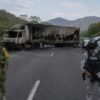 Vista aérea de una carretera en Michoacán con varios vehículos incendiados y obstaculizando la vía, bajo cielo nublado
