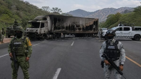 Vista aérea de una carretera en Michoacán con varios vehículos incendiados y obstaculizando la vía, bajo cielo nublado