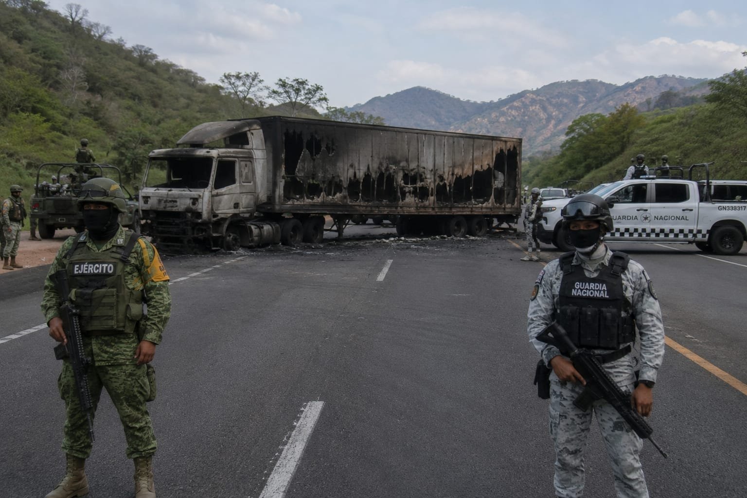 Vista aérea de una carretera en Michoacán con varios vehículos incendiados y obstaculizando la vía, bajo cielo nublado