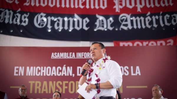 Carlos Torres Piña dialogando con ciudadanos de distintos sectores en un municipio rural de Michoacán, bajo un cielo despejado y con letreros comunitarios visibles