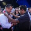 Fotografía de Carlos Torres Piña conversando con ciudadanos en un espacio público, con micrófono y libreta, durante uno de sus recorridos por el estado