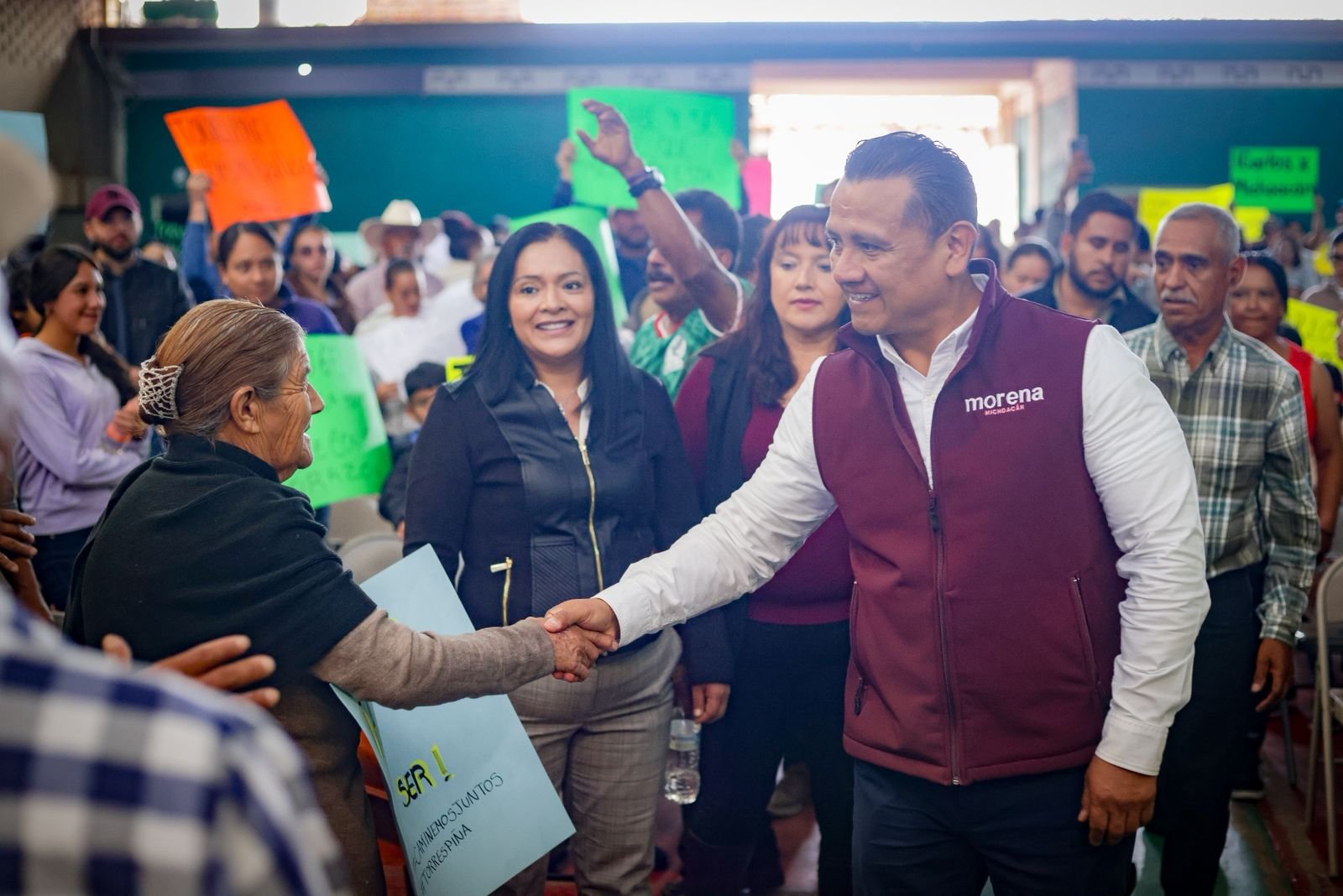 Fotografía de Carlos Torres Piña en diálogo con habitantes de un municipio pequeño de Michoacán, rodeado de paisaje rural y presencia comunitaria