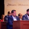 Diputado Conrado Paz Torres junto a representantes mazahuas durante ceremonia solemne en Zitácuaro, con banderas y símbolos indígenas