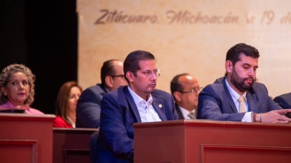 Diputado Conrado Paz Torres junto a representantes mazahuas durante ceremonia solemne en Zitácuaro, con banderas y símbolos indígenas