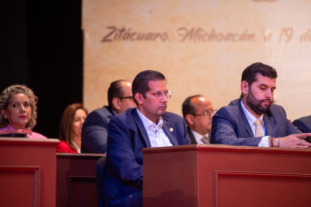 Diputado Conrado Paz Torres junto a representantes mazahuas durante ceremonia solemne en Zitácuaro, con banderas y símbolos indígenas