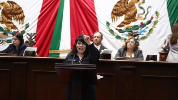 Ilustración simbólica de una mano extendiendo una bandera de Michoacán hacia un globo terráqueo, con siluetas de personas conectadas entre México y Estados Unidos
