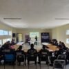 Grupo diverso de policías y personal administrativo de La Piedad participando activamente en un taller sobre apoyo a mujeres víctimas de violencia, con material educativo visible
