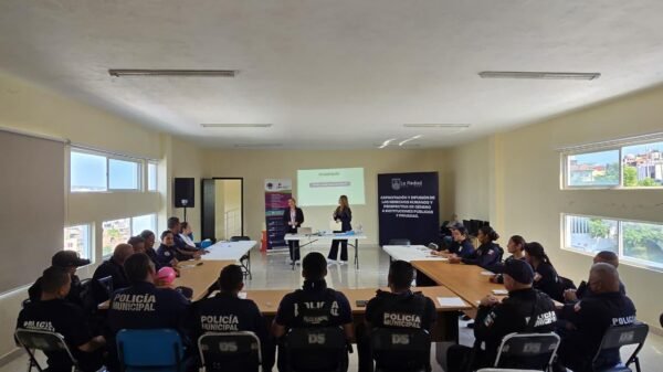 Grupo diverso de policías y personal administrativo de La Piedad participando activamente en un taller sobre apoyo a mujeres víctimas de violencia, con material educativo visible