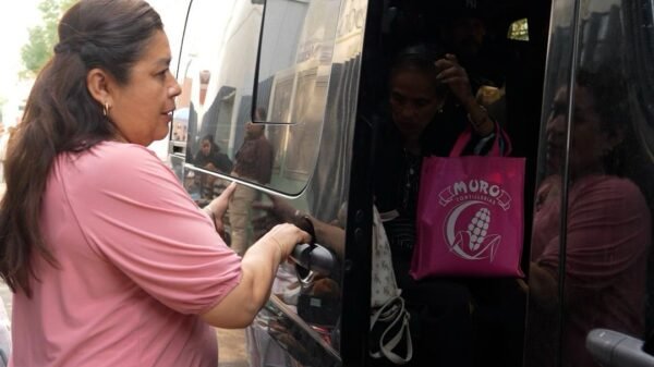 Fotografía de un autobús con logotipo de la Casa de Enlace Legislativo estacionado frente a un centro de salud en Morelia, con personas esperando su turno.