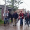 Fotografía de Carlos Torres Piña conversando con habitantes de un municipio michoacano, en entorno rural, con mapa de Michoacán visible de fondo