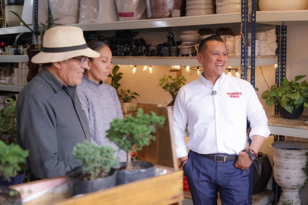 Retrato de Carlos Torres Piña en diálogo con personas de distintas edades y vestimentas, en un entorno rural michoacano, simbolizando escucha activa y conexión territorial
