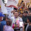 Fotografía de Carlos Torres Piña en una asamblea comunitaria al aire libre en Michoacán, escuchando a ciudadanos sentados en bancas de madera.