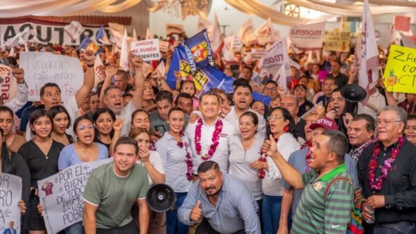 Carlos Torres Piña hablando ante una audiencia en Morelia, con pancartas de 'Plan Michoacán' y 'Sí al Desarme, Sí a la Paz' visibles al fondo