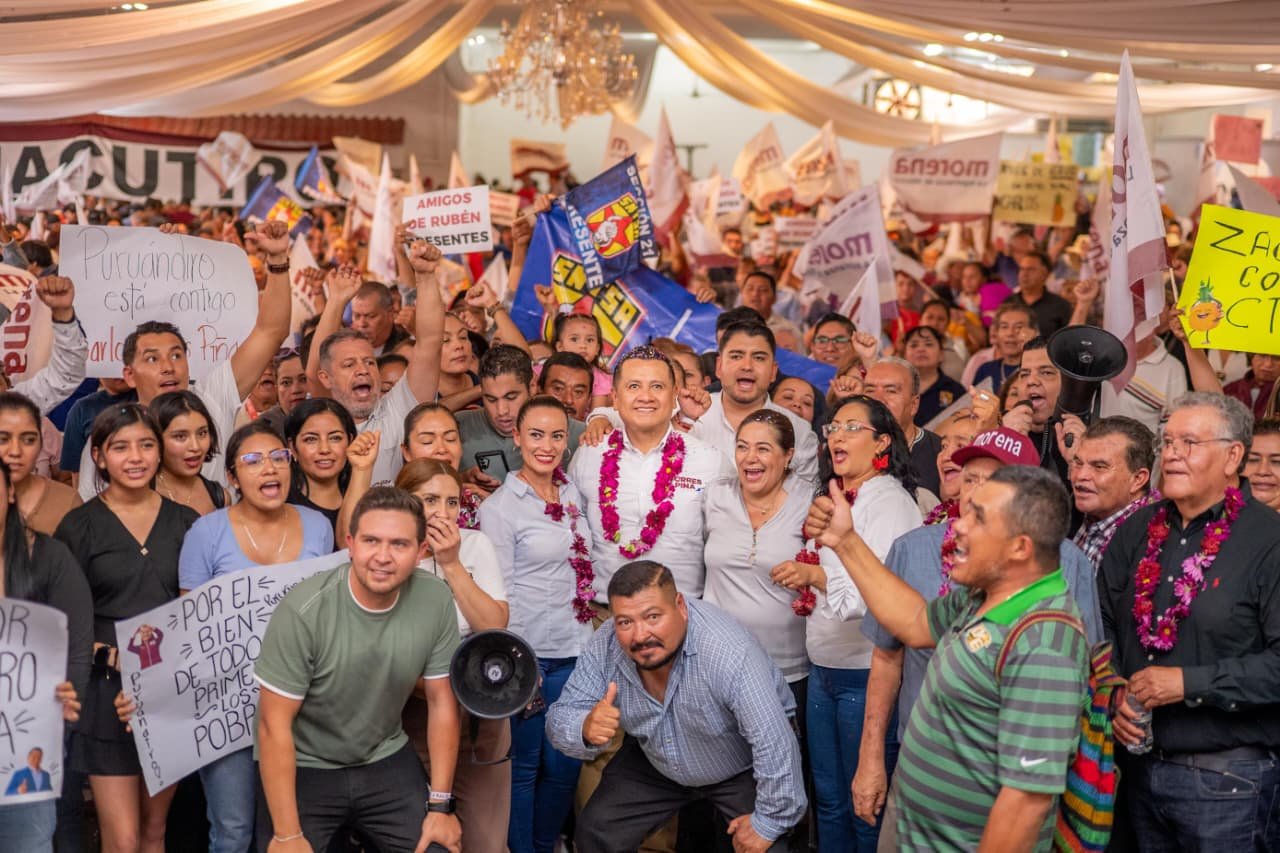 Carlos Torres Piña hablando ante una audiencia en Morelia, con pancartas de 'Plan Michoacán' y 'Sí al Desarme, Sí a la Paz' visibles al fondo
