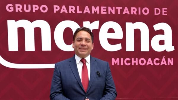 Diputado Iván Arévalo Vera hablando ante micrófonos y bandera de Michoacán durante presentación de informe legislativo en el Congreso estatal