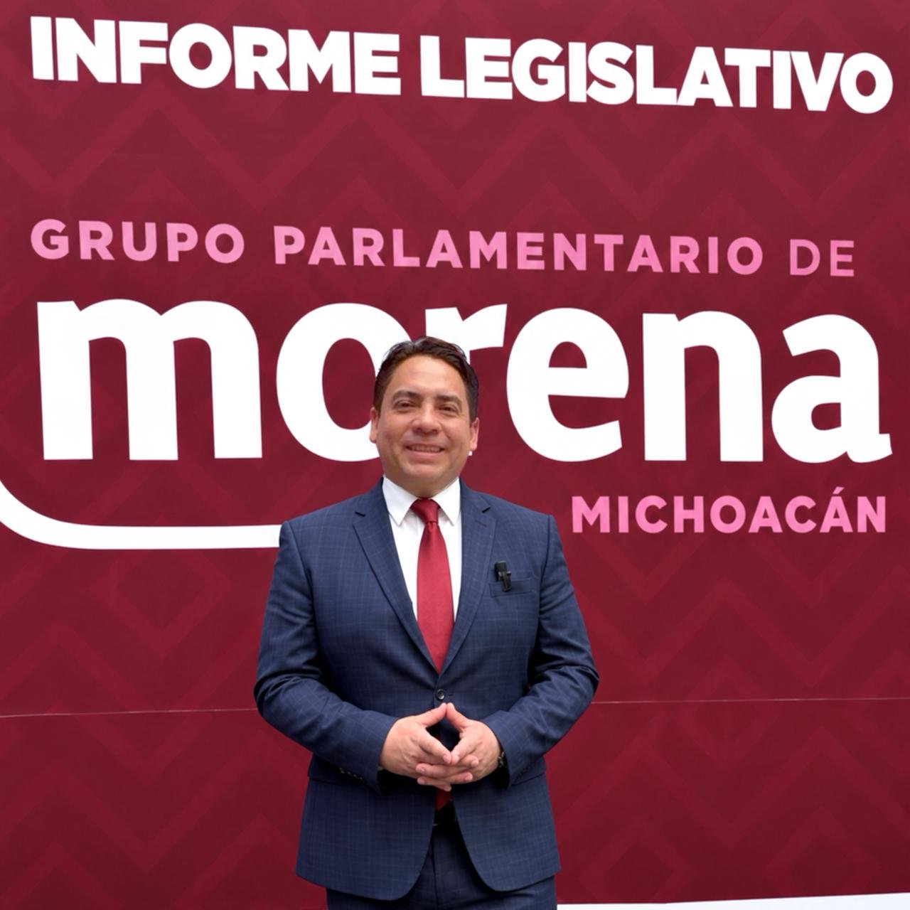Diputado Iván Arévalo Vera hablando ante micrófonos y bandera de Michoacán durante presentación de informe legislativo en el Congreso estatal