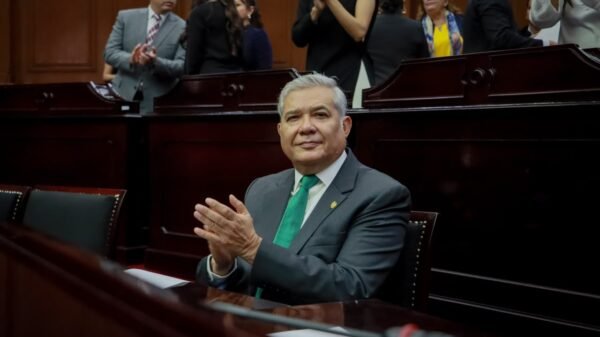 Diputado Juan Antonio Magaña de la Mora hablando ante micrófono en el Congreso del Estado de Michoacán, con bandera del
