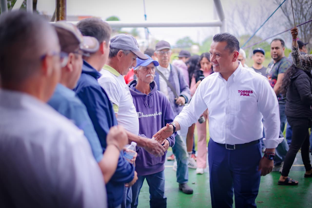 Fotografía de Carlos Torres Piña en reunión con comuneros y productores en una comunidad rural de Michoacán, destacando su
