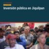 Carlos Torres Piña hablando frente a una multitud en Jiquilpan durante el evento 'La 4T te escucha', con pancartas visibles