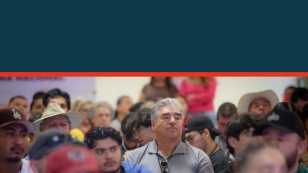 Carlos Torres Piña hablando frente a una multitud en Jiquilpan durante el evento 'La 4T te escucha', con pancartas visibles
