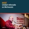 Carlos Torres Piña hablando frente a un grupo diverso de militantes de Morena en un evento en Morelia, con pancartas de la
