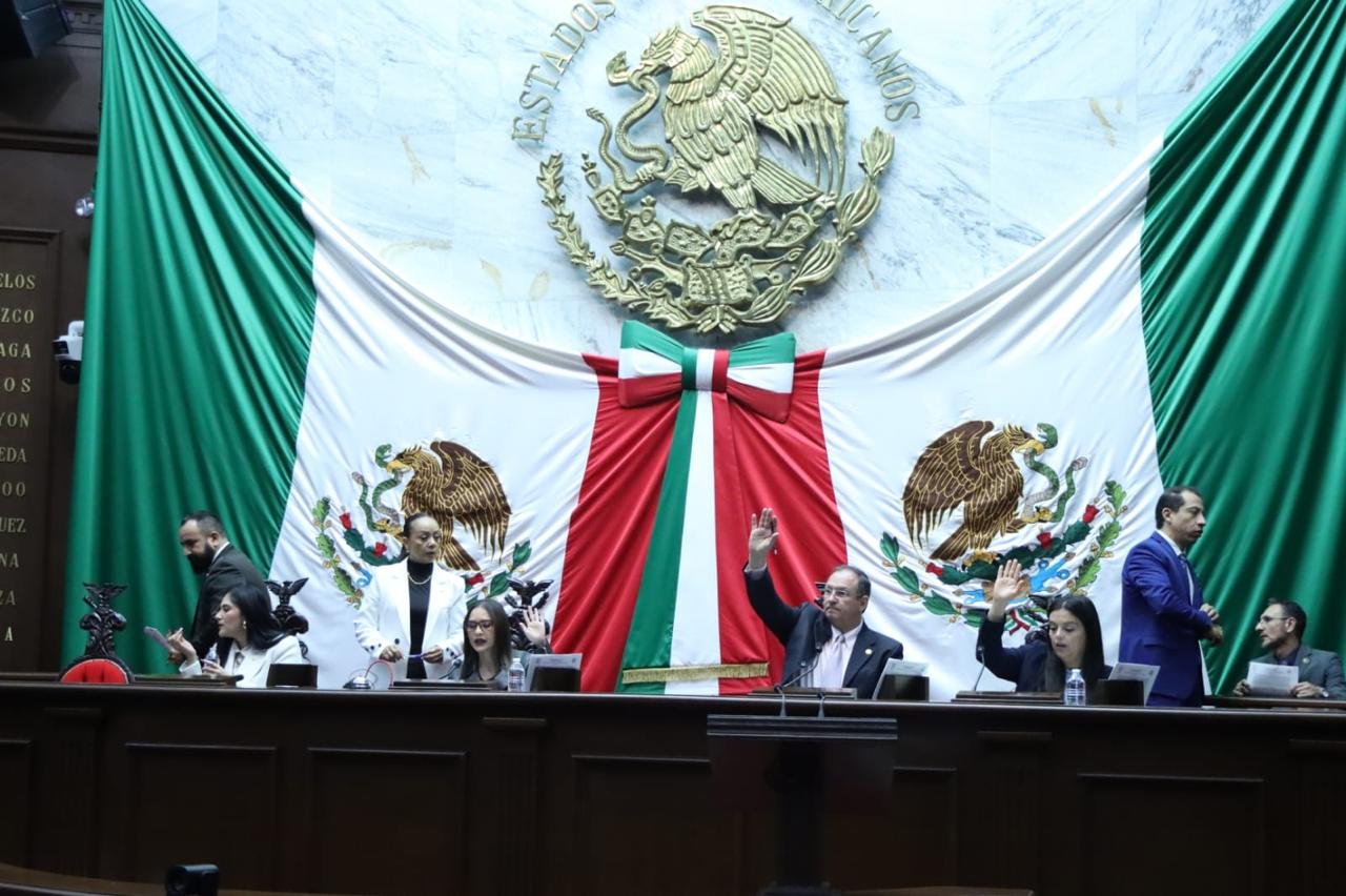 Grupo de artesanos michoacanos trabajando en talleres tradicionales, con símbolos de protección legal y apoyo institucional